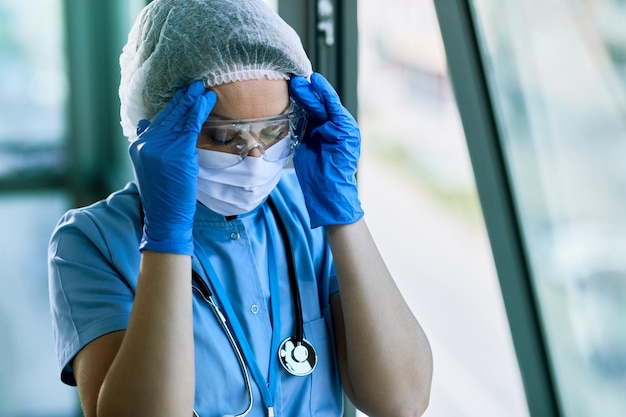 L'infermiera si sente esausta e ha mal di testa mentre lavora in clinica durante la pandemia del virus corona
