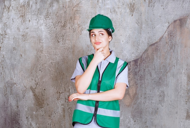 L'ingegnere femminile in uniforme verde e casco sembra confuso e premuroso.