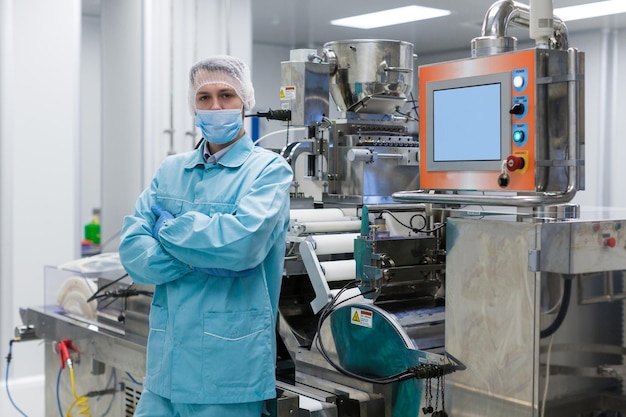 L'operaio di una fabbrica con foto di piante è in piedi vicino alla produzione di macchine in acciaio