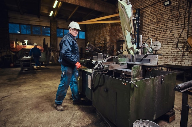 L'operatore della fabbrica di metalli controlla la macchina utensile per il taglio dell'acciaio.