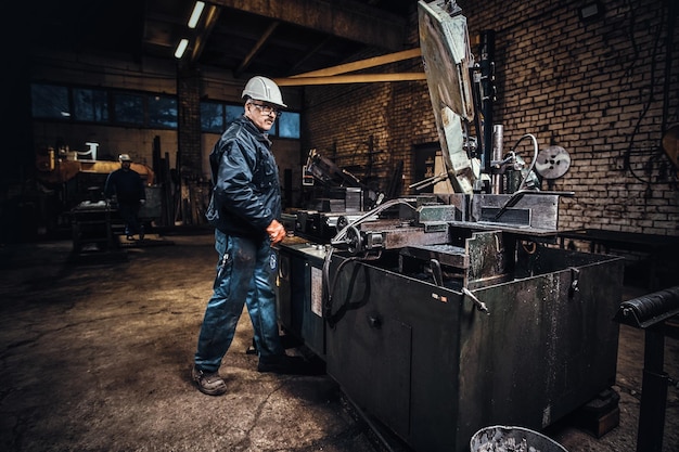 L'operatore della fabbrica di metalli controlla la macchina utensile per il taglio dell'acciaio.