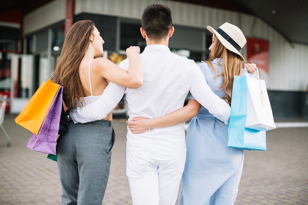 L&#39;uomo abbraccia due donne che vanno a fare shopping