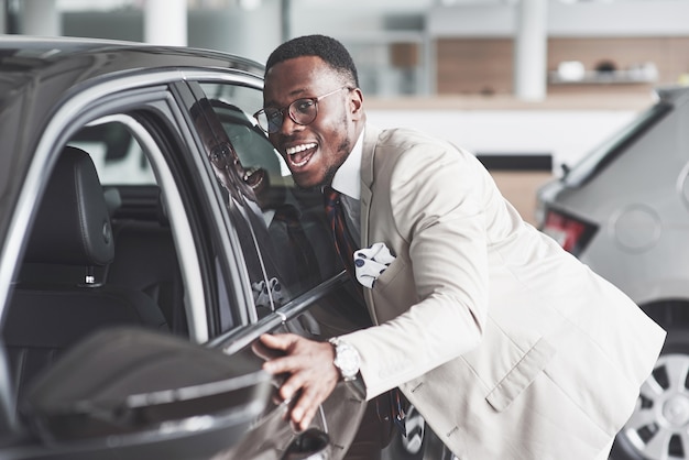 L'uomo africano guardando una nuova auto presso la concessionaria di automobili.