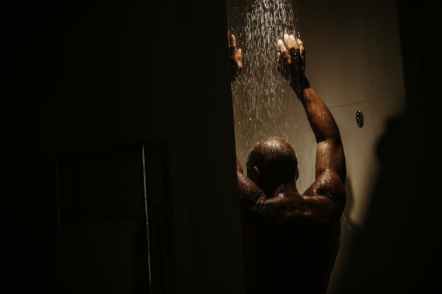 L&#39;uomo afroamericano bello con il torso nudo prende la doccia