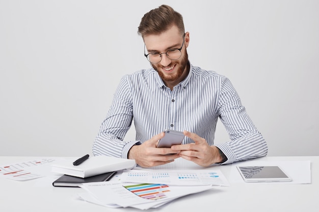 L'uomo alla moda ha messaggi di tipi di pettinatura alla moda su smart phone