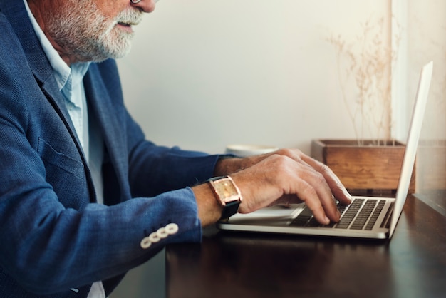 L&#39;uomo anziano sta usando il computer portatile