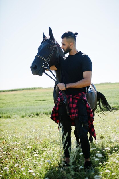 L'uomo arabo con barba alta indossa in nero con cavallo arabo