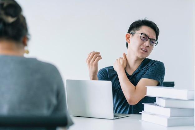 L'uomo asiatico che lavora sodo con la sindrome dell'ufficio ha problemi con una parte del corpo, la spalla, la testa, il collo, la schiena, il concetto di idee per problemi sani