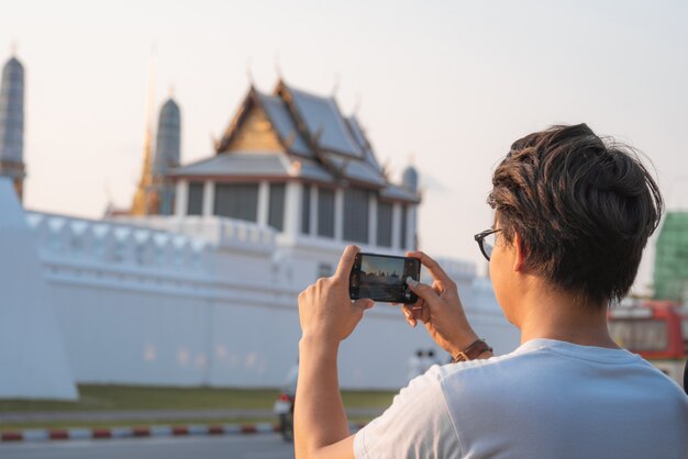 L&#39;uomo asiatico del viaggiatore che per mezzo del telefono cellulare prende un&#39;immagine mentre passa il viaggio di festa a Bangkok, Tailandia