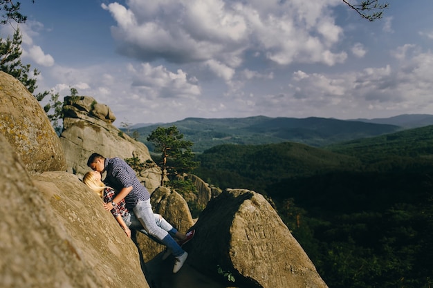 L&#39;uomo bacia donna in piedi davanti a uno splendido paesaggio montano