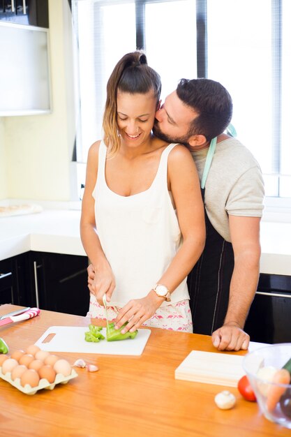 L&#39;uomo bacia sua moglie mentre si prepara il cibo in cucina