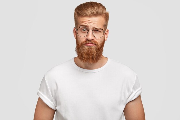 L'uomo barbuto e con la barba perplesso alza un sopracciglio sbalordito, sente qualcosa di inaspettato da un amico