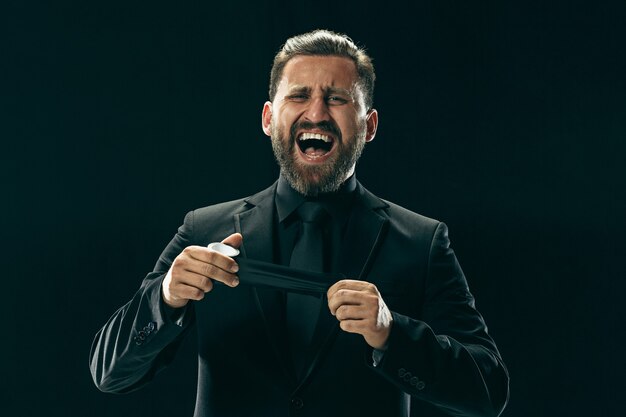 L'uomo bardato in giacca e cravatta. Elegante uomo d'affari su sfondo nero studio. Bellissimo ritratto maschile. Giovane uomo emotivo