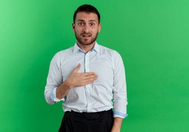 L'uomo bello ansioso mette la mano sul mento isolato sulla parete verde