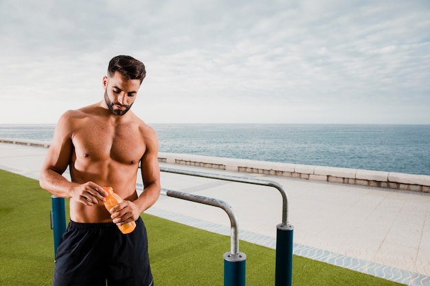 L'uomo bello che ha una pausa e si idrata durante l'allenamento