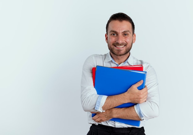 L'uomo bello sorridente tiene le cartelle di file isolate sul muro bianco