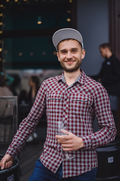 L&#39;uomo bello tatuato su una terrazza estiva in una caffetteria della città è bere vino. Street Cafe.