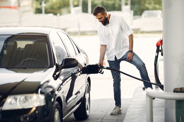 L'uomo bello versa la benzina nel serbatoio dell'automobile