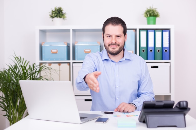 L'uomo caucasico in ufficio offre cooperazione con una stretta di mano