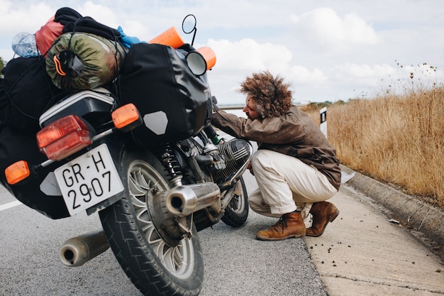 L'uomo cerca di riparare la moto sul lato della strada