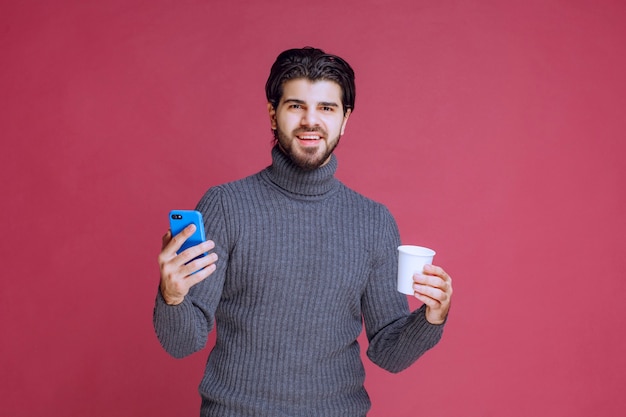 L'uomo che tiene uno smartphone e una tazza di caffè sembra positivo.