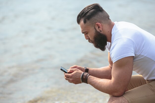 L&#39;uomo con il suo cellulare in riva al lago