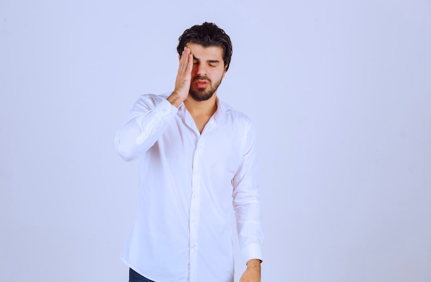 L'uomo con la barba ha mal di testa e si sente male.