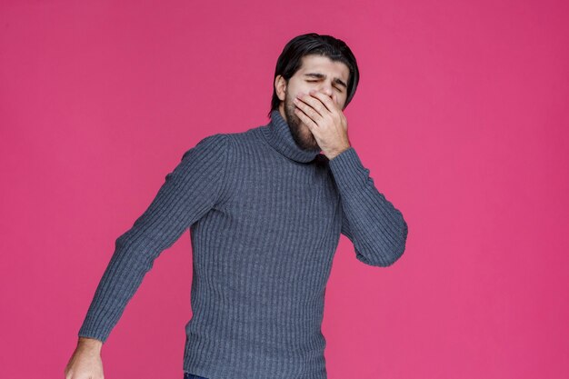 L'uomo con la barba nera sembra esausto e annoiato.