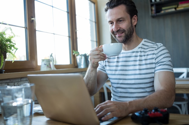 L&#39;uomo con laptop e con una tazza di caffè in caffè