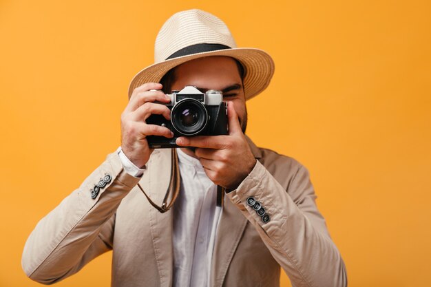 L'uomo con un cappello a tesa larga scatta foto con una fotocamera retrò