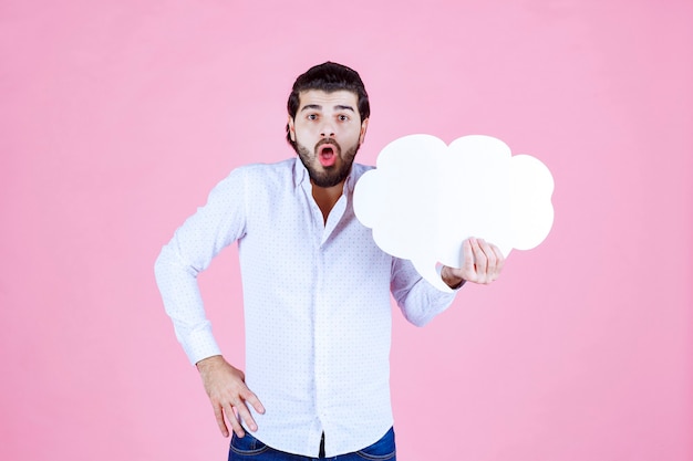 L'uomo con un'ideaboard a forma di nuvola sembra pensieroso.