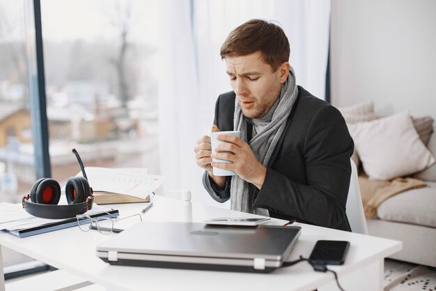 L'uomo con un laptop soffre di tosse e si sente male. Uomo d'affari a casa.