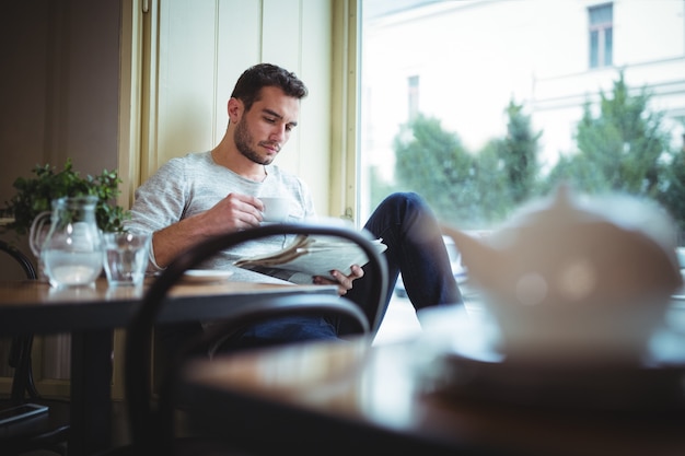 L&#39;uomo con una tazza di caffè mentre legge il giornale