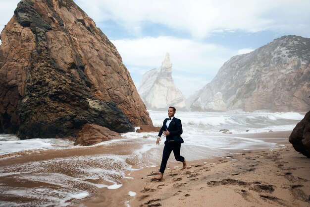 L'uomo corre sulla sabbia bagnata tra le rocce