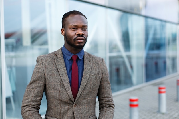 L&#39;uomo d&#39;affari nero afroamericano alla moda posa in un vestito prima di una costruzione moderna