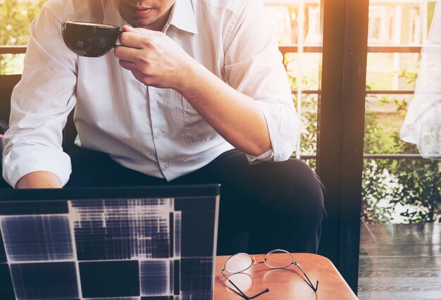 L&#39;uomo d&#39;affari sta lavorando con il suo computer nella caffetteria