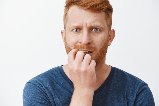 L'uomo dai capelli rossi è preoccupato, si sente spaventato, si morde le unghie e lo fissa nervosamente, si sente ansioso