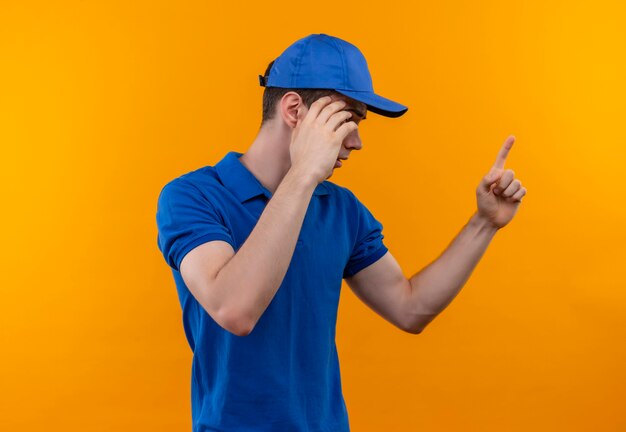 L'uomo del giovane costruttore che indossa l'uniforme e la protezione della costruzione spiega qualcosa con un dito