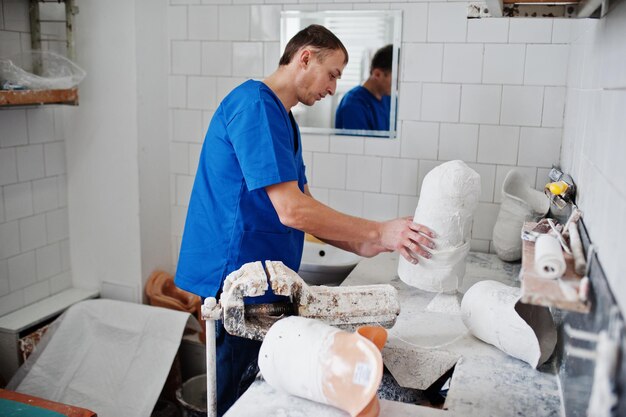 L'uomo del protesista che fa la gamba protesica mentre lavora in laboratorio realizza un modello di gesso