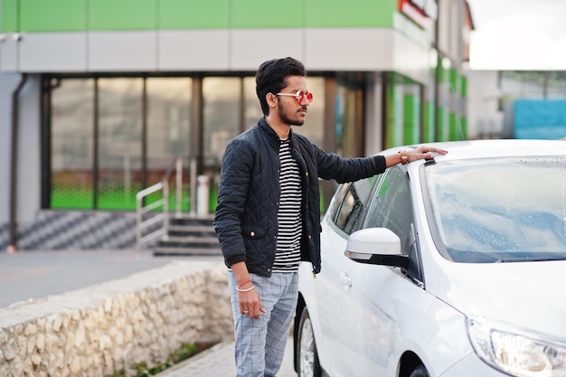 L'uomo del sud asiatico o il maschio indiano indossano occhiali rossi vicino al suo trasporto bianco sull'autolavaggio