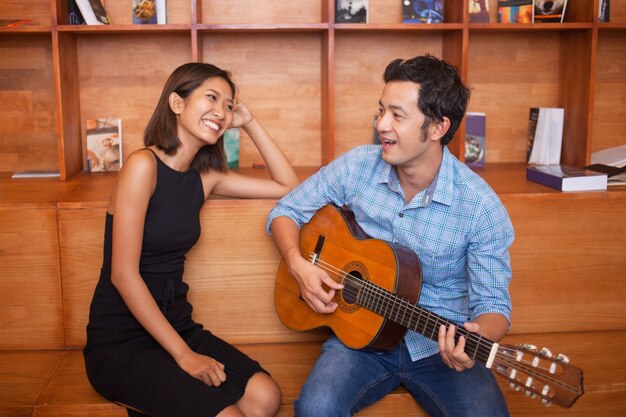 L&#39;uomo di canto e suonare la chitarra per donna sorridente