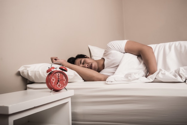 L&#39;uomo dorme nel letto con allarme rosso in primo piano