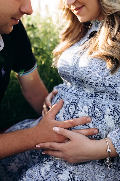 L&#39;uomo e la donna incinta si siedono insieme in un&#39;erba verde piena di fiori di lavanda viola