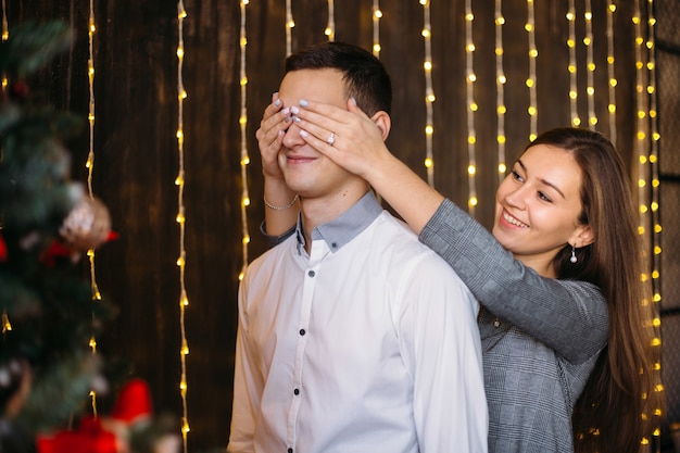 L&#39;uomo e la donna sembrano belle in posa prima di un albero di Natale rosso