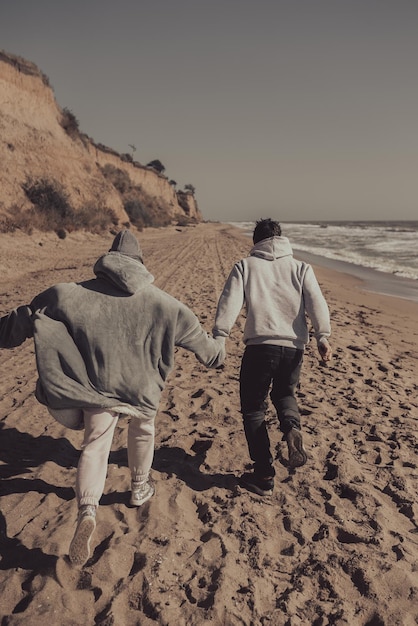 L'uomo e la donna si divertono a correre lungo la riva del mare