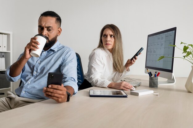 L'uomo e la donna sono dipendenti dai loro telefoni anche al lavoro