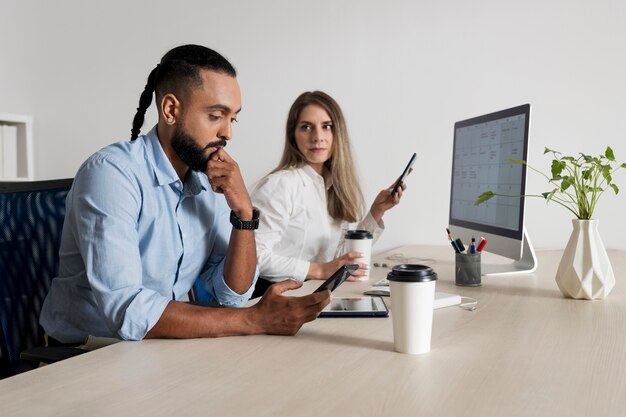 L'uomo e la donna sono dipendenti dai loro telefoni anche al lavoro