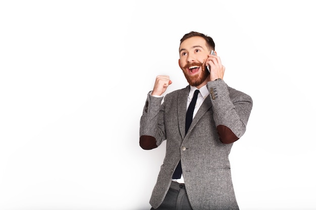 L&#39;uomo felice in vestito grigio parla sul telefono