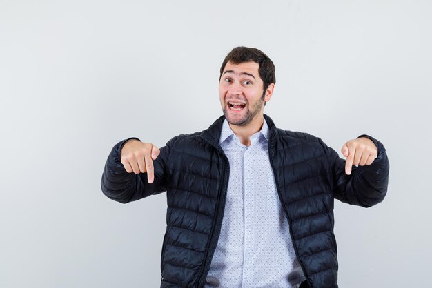 L'uomo felice sta puntando verso il basso con gli indici su sfondo bianco