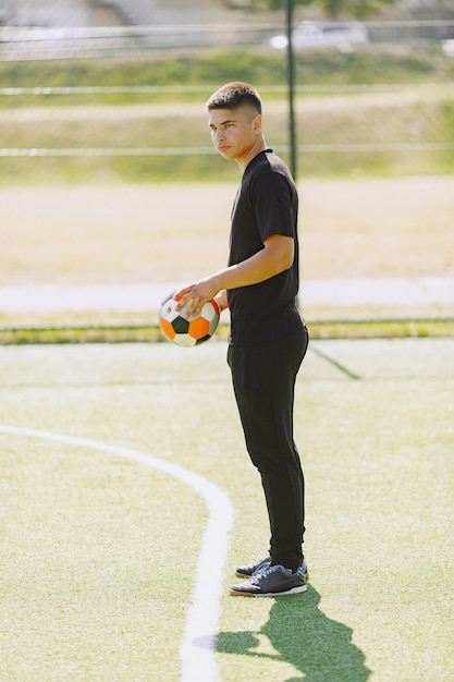 L'uomo gioca a socerl al parco. Torneo su mini-footbal. Ragazzo in tuta sportiva nera.